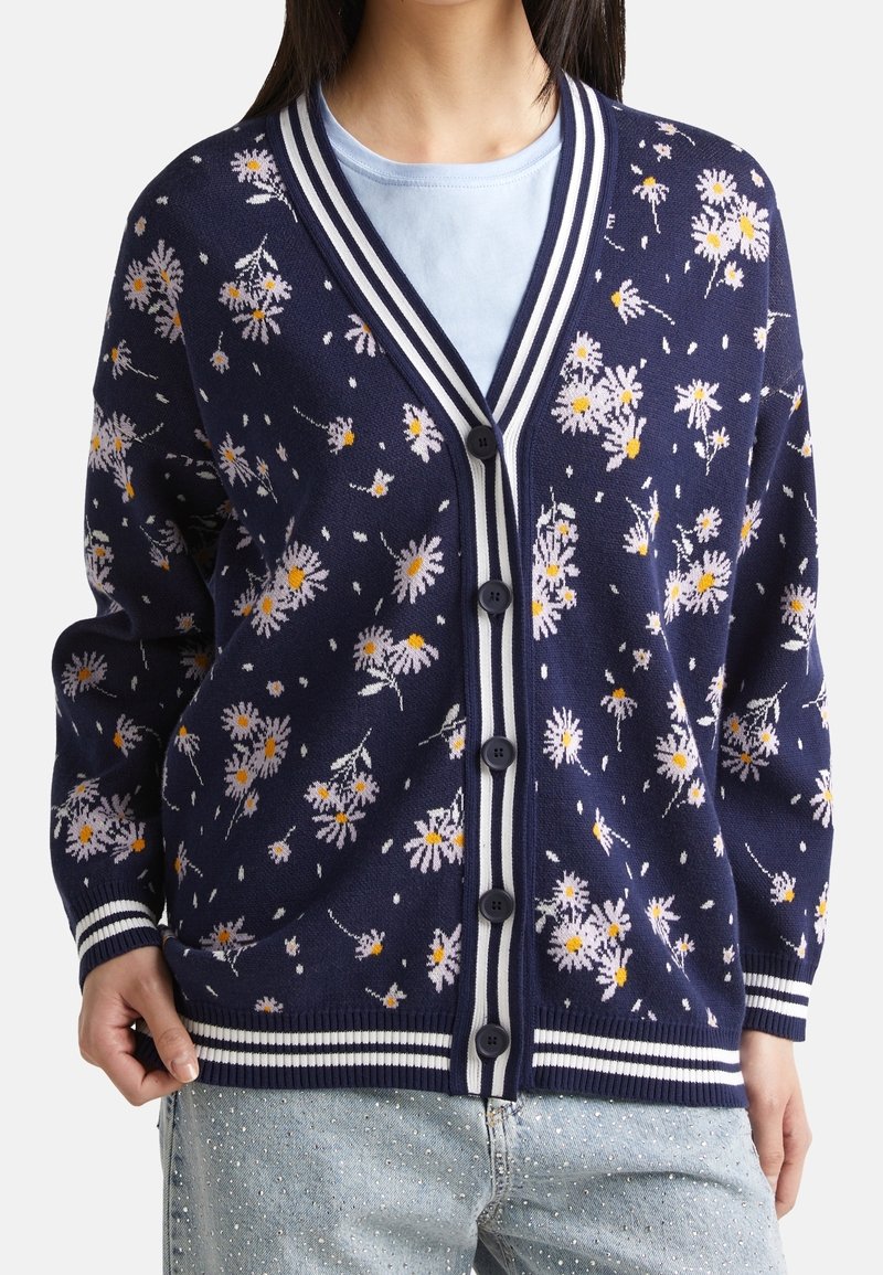 Marinblå cardigan med vitt och ljusrosa blommönster, knappstängning, randig krage och ärmslut, mjukt stickat material, långa ärmar.