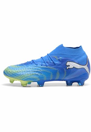 Bota de fútbol Puma azul con cuello alto en el tobillo, detalles en color lima y tacos moldeados, mostrada de perfil sobre un fondo blanco.