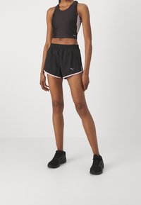 Mustat urheilulliset tank top ja shortsit vaaleanpunaisilla yksityiskohdilla, joissa on tyköistuva muotoilu, joustava vyötärö ja logotiedot shortseissa.