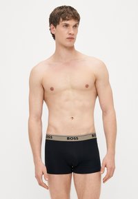 Μαύρα ανδρικά εσώρουχα τύπου boxer με ελαστική μέση σε χρυσή απόχρωση που φέρει το λογότυπο «BOSS». Ομαλή υφή υφάσματος, εφαρμοστός σχεδιασμός και μεσαίο μήκος.