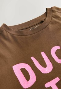 Tricou maro cu decolteu rotund, cu text roz mare care spune "DUC." Țesătura pare moale, cu o textură netedă.
