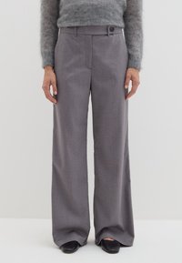 Grijze wijde broek gemaakt van textuurstof, met een knoopsluiting en riemlussen. Gestyled met een aansluitende, grijze fuzzy trui en zwarte schoenen.