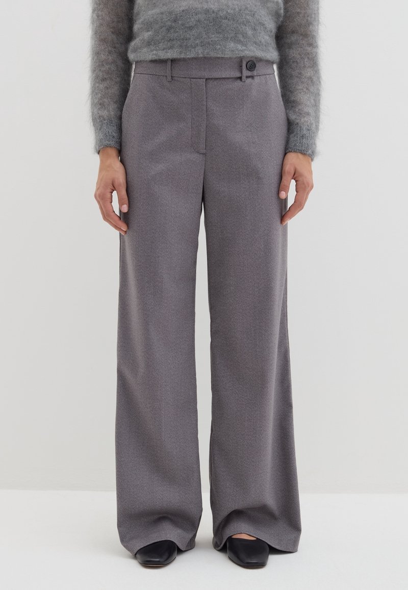 Grijze wijde broek gemaakt van textuurstof, met een knoopsluiting en riemlussen. Gestyled met een aansluitende, grijze fuzzy trui en zwarte schoenen.