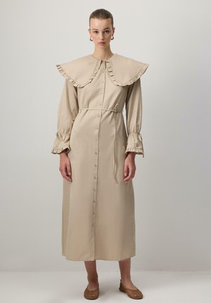 Abito beige a maniche lunghe con colletto arricciato, chiusura con bottoni sul davanti e vita regolata da una cintura. Presenta maniche arricciate e una silhouette dritta.