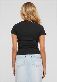 Must have lühikeste varrukatega must T-särk, millele on kombineeritud helesinine denimpõhi, millel on taskud ja tikandiga logo detail taga.