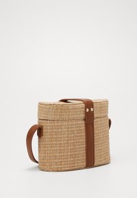 Borsa rettangolare in paglia intrecciata con finitura naturale, cinturino in pelle e chiusura a fibbia semplice. Presenta due manici per il trasporto.