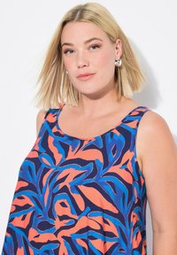 Vestido sin mangas con un vibrante estampado botánico en azul, naranja y marino. Tejido suave con un corte relajado y escote redondo.
