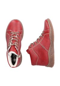 Rote Leder-Stiefeletten mit einem weichen, fellgefütterten Innenfutter, ausgestattet mit Metallösen, Schnürsenkeln und einer texturierten Gummisohle. Seitlicher Reißverschluss als Detail.