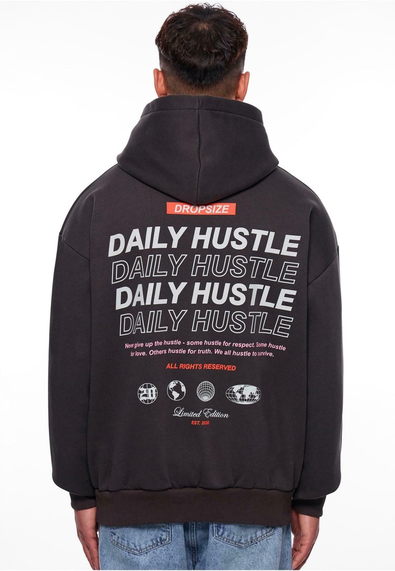 Dunkelgrauer Kapuzenpulli mit einem großen Grafikdruck auf der Rückseite. Mit auffälligem weißen und roten Text, gerippten Bündchen und einer Kängurutasche ausgestattet.