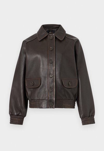 Σκούρο καφέ δερμάτινο μπουφάν με κουμπιά μπροστά, δύο τσεπάκια με κουμπιά και πτερύγια, ελαστικά μανσέτες και μέση, παρουσιασμένο σε απλό φόντο.