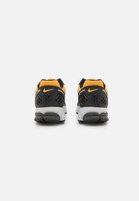 Baskets Nike noires et jaunes avec une tige en maille, un design de talon distinctif et une semelle rembourrée. Comprend un motif texturé noir.