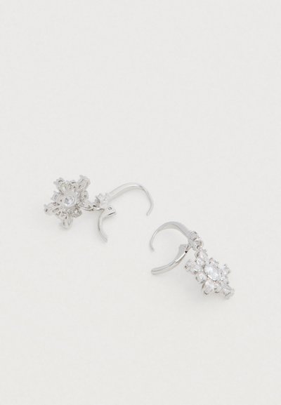 Brincos argola de prata com um design floral adornado com cristais transparentes. Os ganchos dos brincos são suavemente curvados e brilhantes.