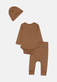 Ensemble pour bébé marron comprenant un body à manches longues, un legging assorti et un bonnet, fabriqué en tissu doux et texturé.