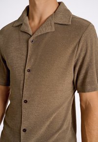 Bruine korte mouw shirt van textuurstof met een kraag, voorzien van donkerbruine knopen langs de voorflap.