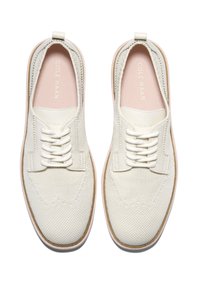 Sneakers bianche in maglia con una parte superiore testurizzata e cuciture tono su tono. Presentano un design con lacci e una suola chiara. Punta liscia e arrotondata.