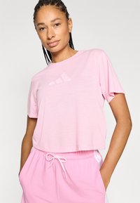 Rosa kurzärmeliges T-Shirt aus leichtem Stoff, mit Rundhalsausschnitt und kurzen Ärmeln, versehen mit einem dezenten Logo auf der Brust.