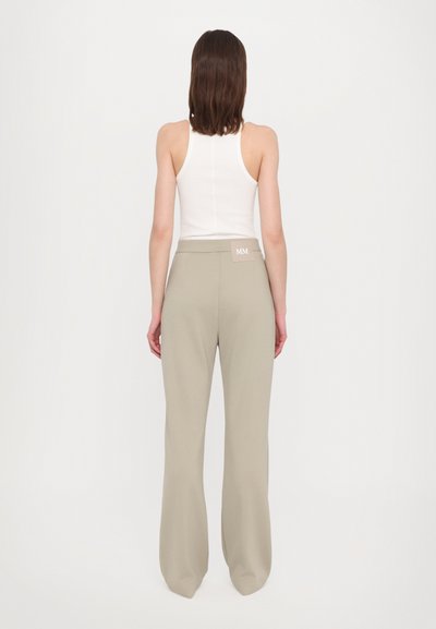 Gai bēšas platleņķa bikses, izgatavotas no gludas auduma, ar augstu jostasvietu un mazu birku ar "MM" aizmugurējā jostas daļā.