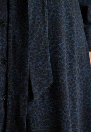 Lühikeste varrukatega kleit tumesinisest kangast, millel on tekstuurne leopardimuster. Omab nööpe ja lipsuga aktsenti vööl.