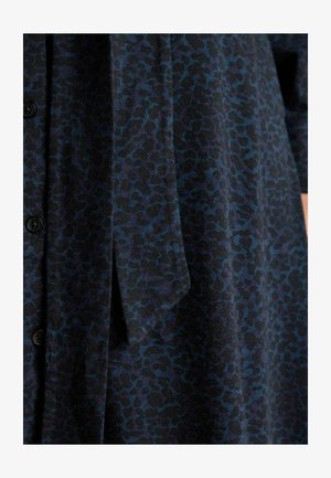 Kratké rukávy šaty v tmavomodrom materiáli s textúrovaným leopardím vzorom. Obsahuje gombíky a viazací akcent na páse.