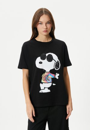 T-shirt noir en coton avec un design coloré de Snoopy portant des lunettes de soleil et le texte "JOE COOL" sur un shirt tie-dye. Manches courtes, coupe décontractée.