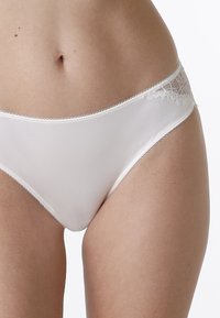 Slip in cotone bianco con merletto in vita, caratterizzato da una finitura liscia e una dolce curvatura sui fianchi.