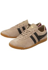 Sneaker in suede beige chiaro con strisce nere, dotate di un logo dorato. Suola in gomma con un motivo testurizzato per una migliore aderenza. Design minimalista.