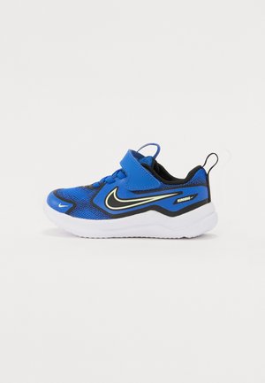 Kék sportcipők hálós felsőrésszel, fekete részletekkel, fehér talppal és tépőzáras pánttal. Jellemzője egy kiemelkedő sárga Nike logó.