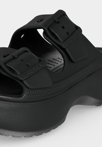 Sandale à plateforme noire avec deux sangles réglables à boucle et semelle intérieure texturée conçue pour le confort et un usage décontracté.