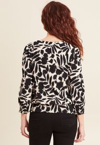 Schwarz-weiße Bluse mit floralem Druck, elastischem Saum und gerafften Ärmeln, ausgestattet mit einem strukturierten Stoff und einem lockeren Schnitt.