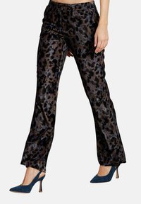 Samt-Hosen mit einem metallischen Leopardenmuster in Braun und Schwarz. Mit geradem Schnitt und Seitennähten. Kombiniert mit blauen Absätzen.