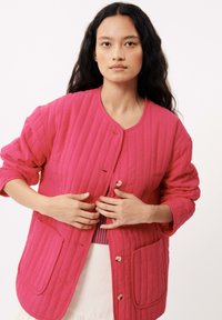 Veste matelassée rose avec un col rond, fermeture à boutons et deux poches avant ; possède un motif texturé cousu et des manches longues.