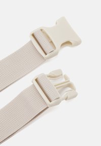 Beige nylon strap with two plastic buckles, featuring a textured surface and secure locking mechanism for adjustable fit.