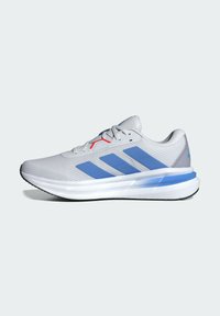 Chaussure de sport gris clair avec des rayures bleues, dessus en maille texturée, col rembourré, accents rouges et semelle blanche rembourrée avec un profil en noir.