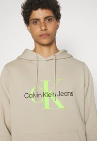 Calvin Klein Jeans SEASONAL MONOLOGO REGULAR HOODIE - Sudadera - plaza taupe/acid light