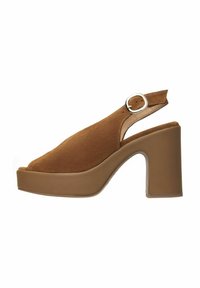 Talons compensés ouverts en daim marron, avec un épais talon bloc, un bout ouvert et une boucle en argent sur la sangle réglable.