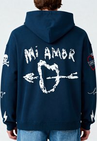 Felpa con cappuccio blu navy caratterizzata da testo grafico bianco "Mi Amor", cuori, teschi, frecce e motivi di fulmini sulla parte posteriore e sulle maniche.