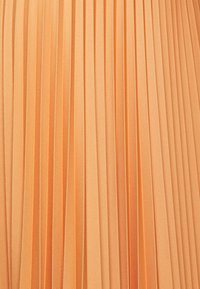 Gonna plissettata in tessuto arancione chiaro, con strisce verticali e una texture liscia. Le pieghe creano profondità e schemi uniformi.