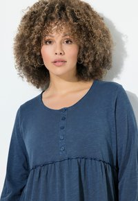 Navyblaues Langarmoberteil mit rundem Ausschnitt, Knopfdetails und gerafftem Textur am Bund. Weicher Stoff mit einem leichten Glanz.