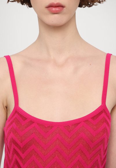 Top in rete rosa con motivo a zigzag, spalline sottili e scollatura a barchetta. La texture sembra leggera e semi-trasparente.
