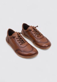 Zapatos de cuero marrón con superficie texturada, puntera redondeada, diseño con cordones y suela de goma flexible, que presentan una estructura casual y ligera.