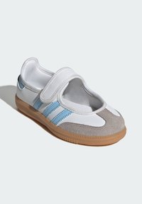 Biele a šedé športové topánky s modrým prúžkom, so suchým zipsom, gumenou podrážkou a polstrovaným interiérom.