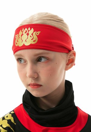 Red fabric headband with a gold flame design, worn with a black shirt featuring gold accents. Clear focus on the headband's texture and color.