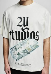 Kremo spalvos medvilniniai marškinėliai su ryškiu juodu tekstu ir atspausdintu 100 dolerių kupiūros dizainu apatinėje dalyje. Slogan'as atspausdintas apačioje.