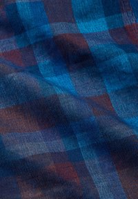 Kék és sötétvörös kockás szövet, látható textúrával és redőkkel, mely egy puha és szőtt anyagmintát mutat.