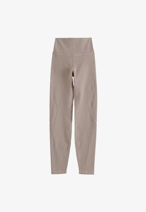 Leggings beige hechos de una tela elástica, con una cinturilla ancha y detalles de costura a lo largo de las piernas, diseñados para ofrecer comodidad y flexibilidad.