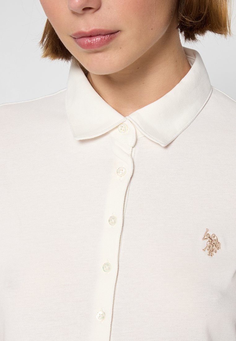 Crème polo shirt van een gestructureerde stof, met een klassieke kraag, een sluiting met knopen aan de voorkant en een klein geborduurd logo op de borst.