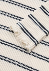 Kremowa bluzka z żeberkowej dzianiny z granatowymi poziomymi paskami. Posiada falbanki na końcach rękawów oraz teksturowane wykończenie.