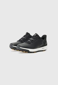 Pantofi sport negri cu un material superior neted și texturat, cu accente gri, talpă intermediară albă și talpă din cauciuc cu aderență, prevăzută cu cuie portocalii.