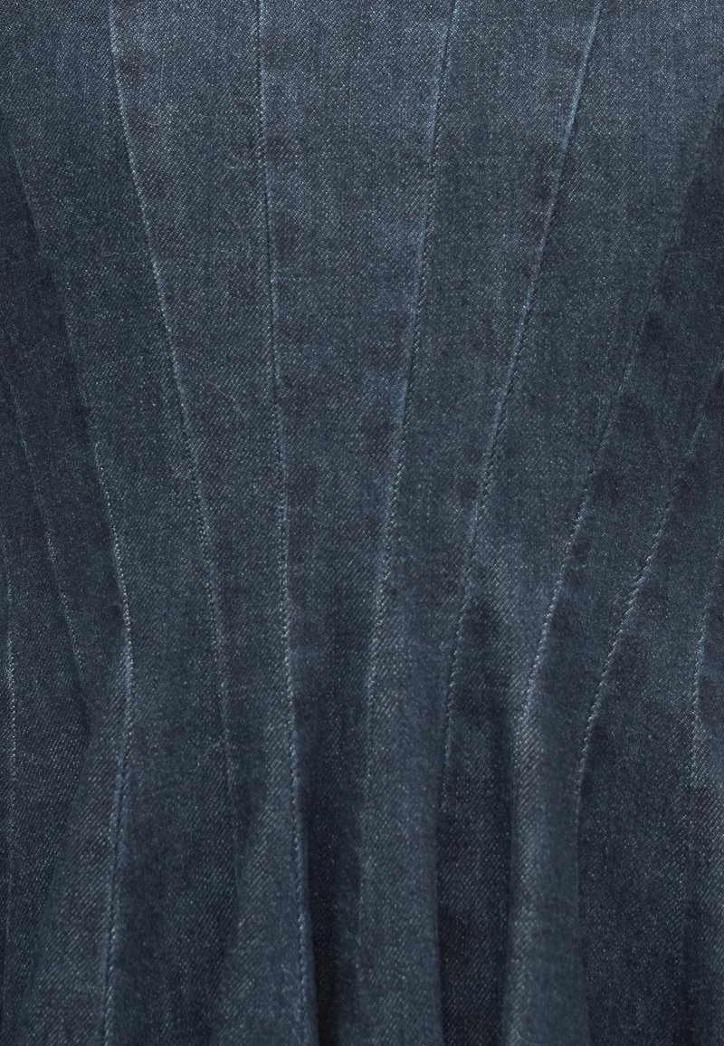 Tissu en denim foncé avec des détails de couture verticaux. La texture est lisse avec un léger éclat, mettant en valeur le design structuré.
