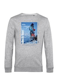 Felpa grigia con una grande stampa grafica in blu e bianco, che ritrae un alpinista. Include il testo "DAL 1981" e un design della bussola.